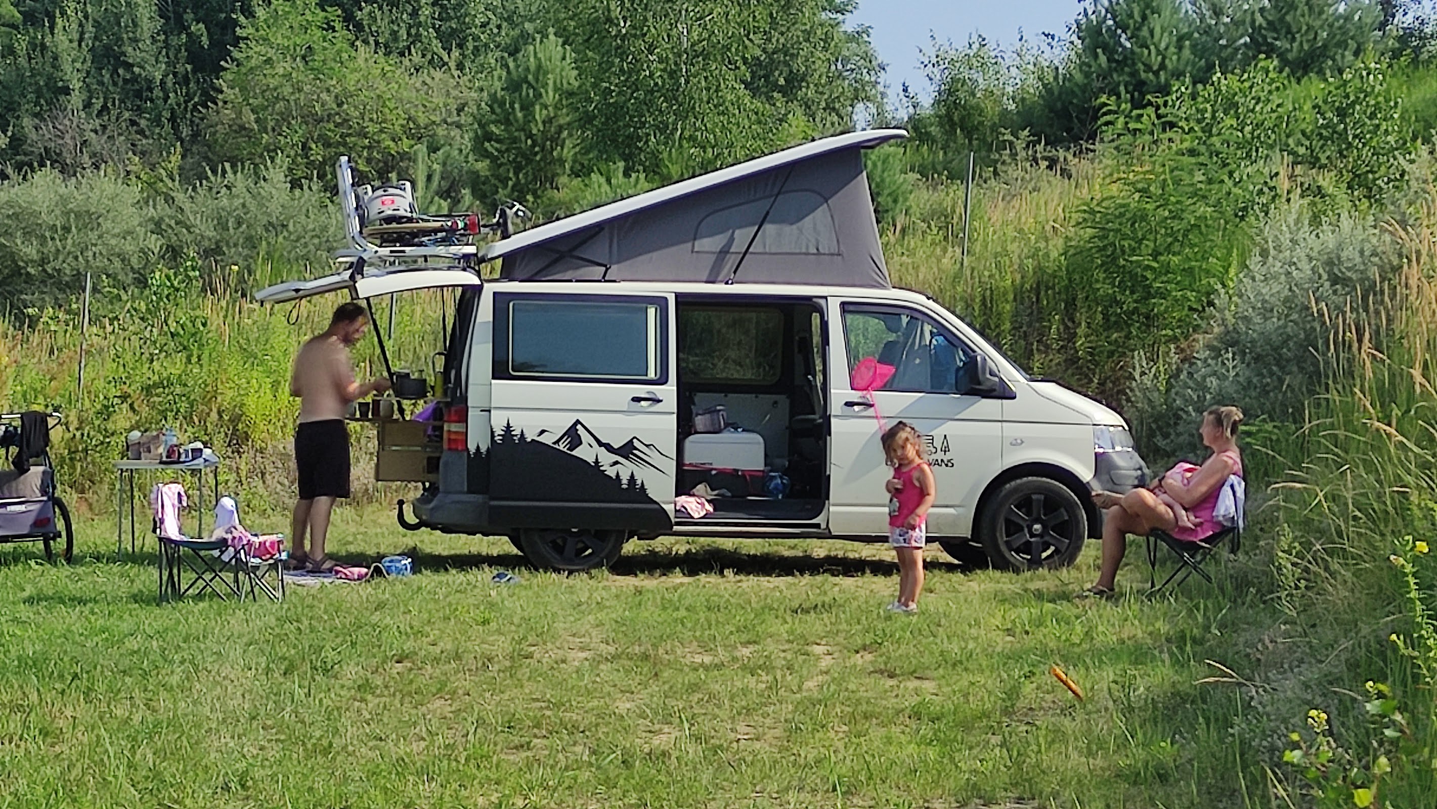 Rodzina odpoczywająca przy kamperze na trawie